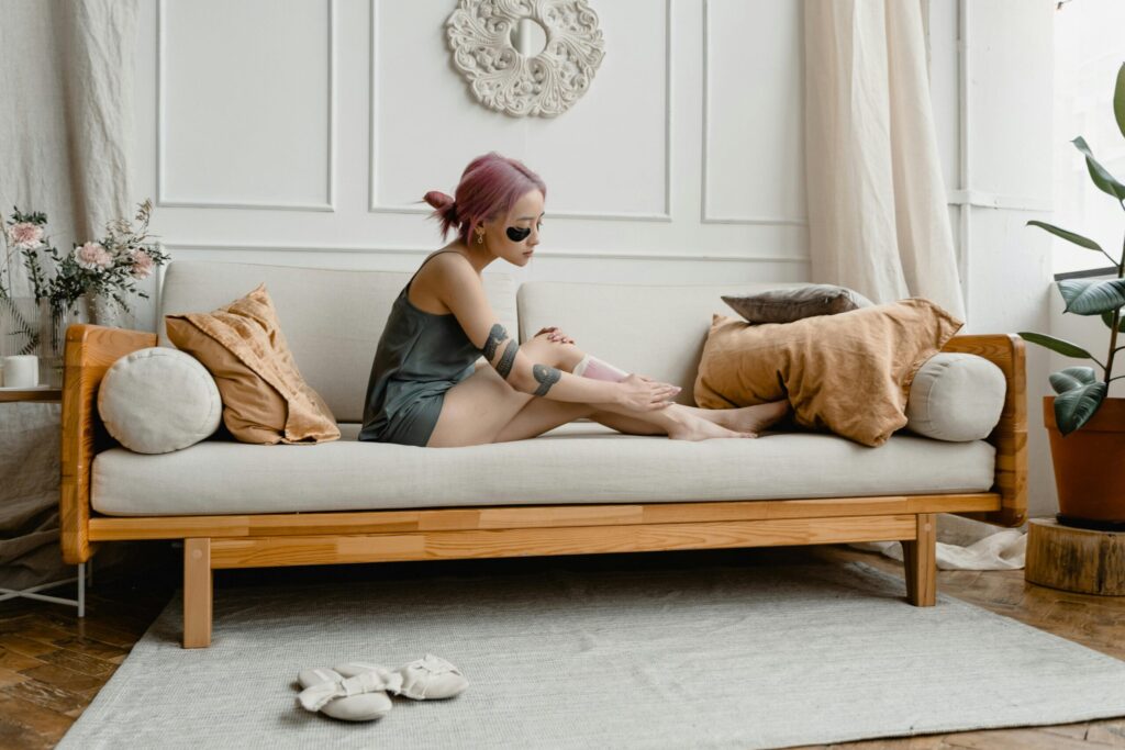 An adult woman waxing her legs at home, showcasing a self-care beauty routine.