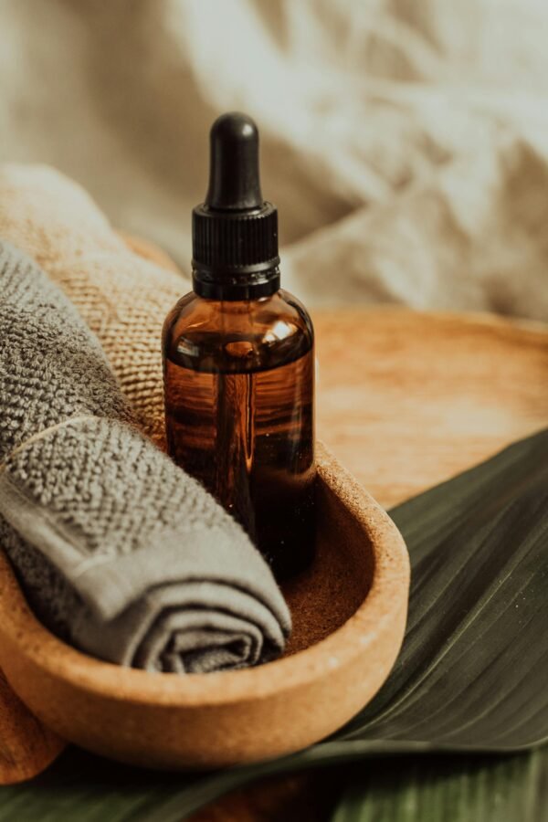 Wellness Essentials You Need for Better Health A soothing setup of skincare essentials featuring a dropper bottle, towel, and leafy backdrop, perfect for wellness inspiration.